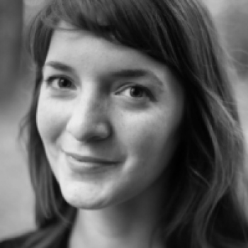 Young woman with pale skin and dark hair smiles at camera