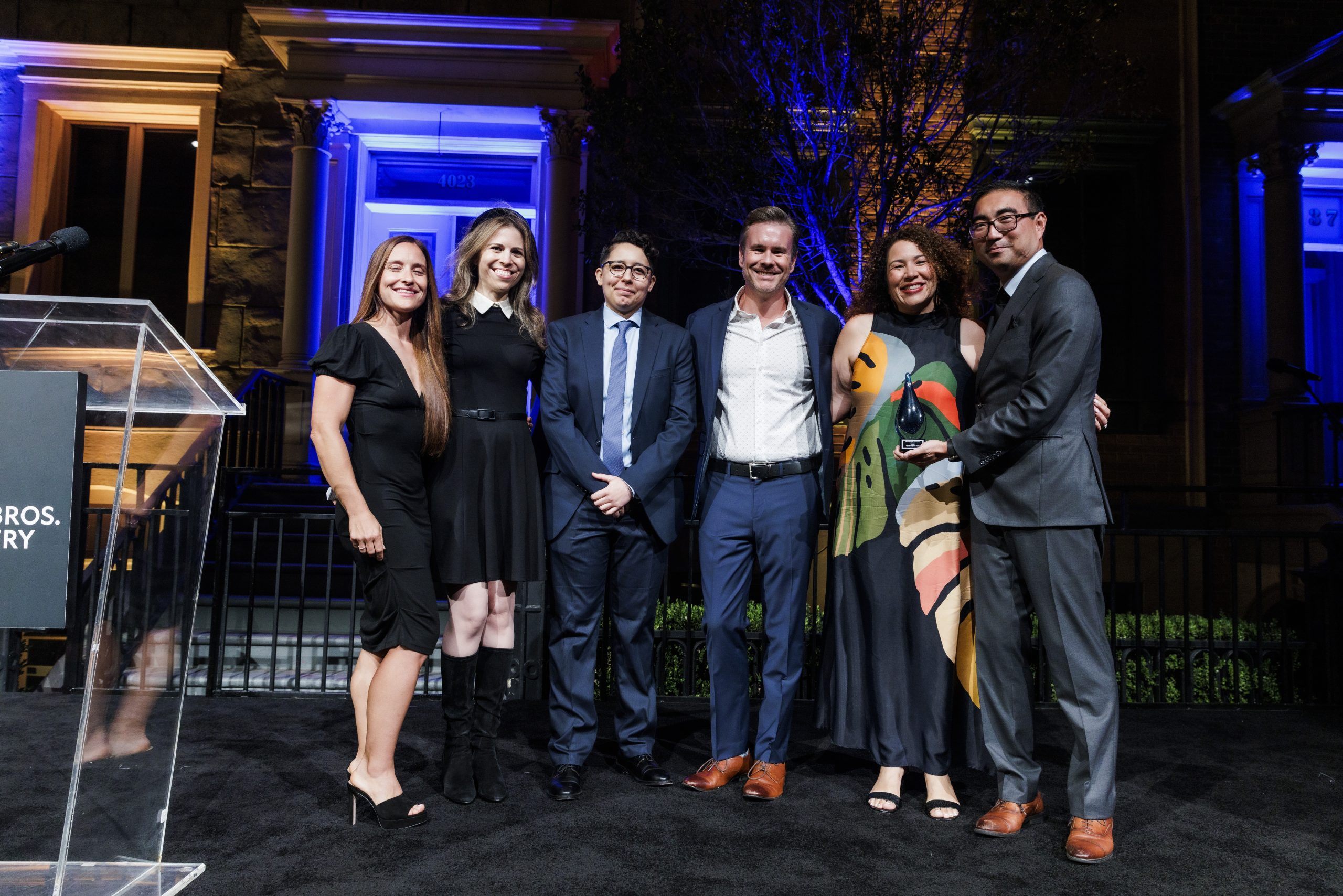 Posed photo of 6 people facing the camera as Noemi Romero of Amgen accepts Cancer Vanguard Award