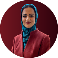 Saddia Khan head shot: A blue scarf frames Saddia's face. She wears a red blazer and smiles directly at the camera.